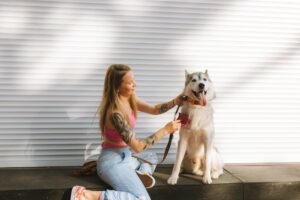 Young woman in pink top grooming her Siberian Husky dog outdoors.